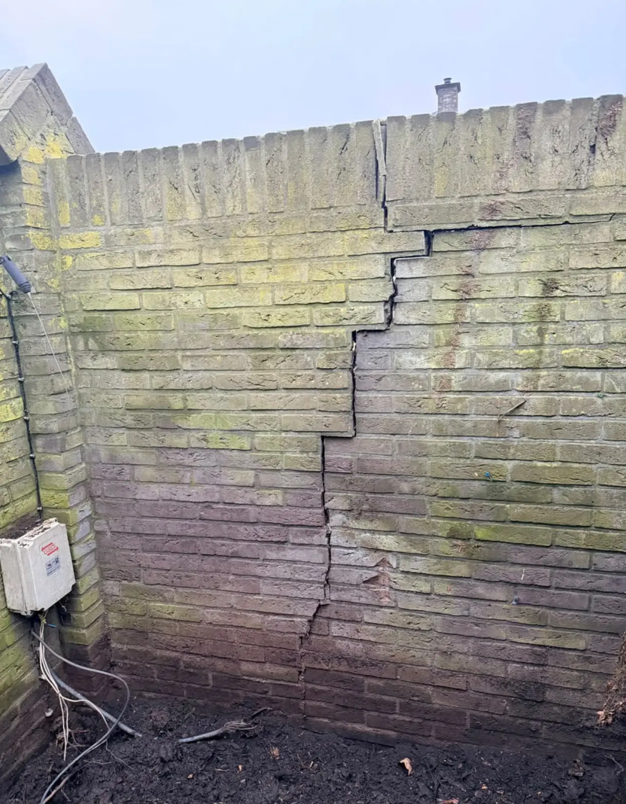 Tuinmuur met een trapscheur en groene aanslag